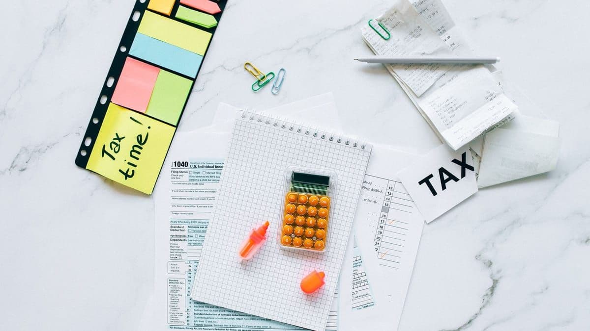 Indian tax documents, a calculator and pen laid out on a marble table