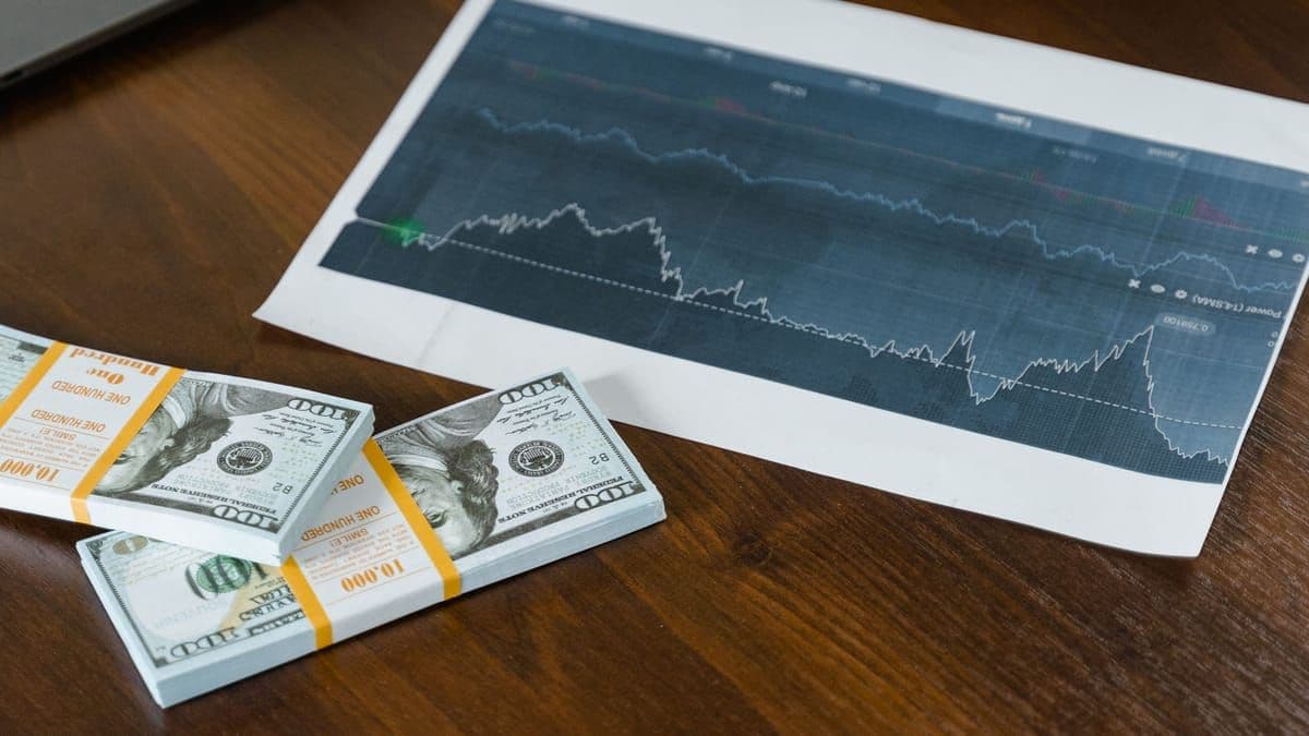 Cash, a printed stock chart and a laptop on a desk