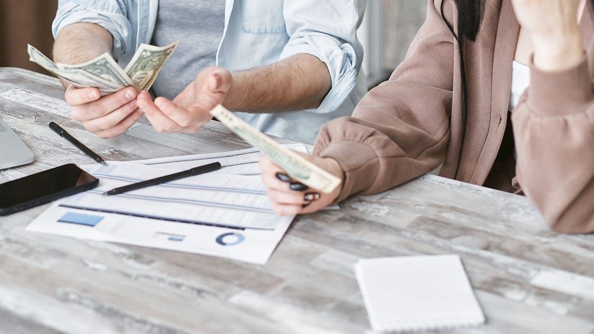 A couple at home counting cash and looking worried over their finances
