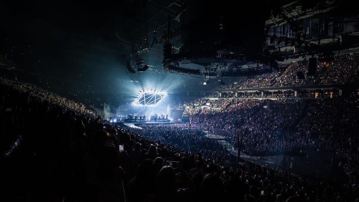 A packed concert crowd silhouetted against bright stage lights